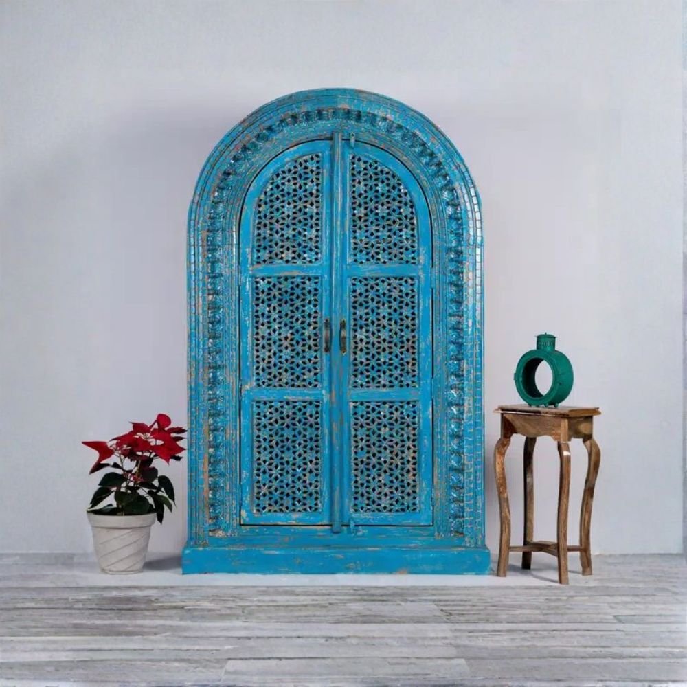 Handcrafted distressed blue carved wooden wardrobe cabinet with arched doors – front view.