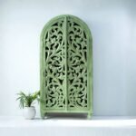 Handcrafted green carved wooden wardrobe cabinet with arched doors – front view.